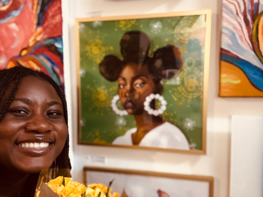 Aishat beside exhibited portrait at Boomer Gallery